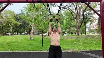 asiatisk man praktiserande gymnastik håller på med gymnastik bar och ring övningar och stretching och vilar för sporter. video