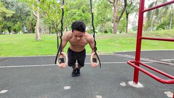 asiatisk man praktiserande gymnastik håller på med gymnastik bar och ring övningar och stretching och vilar för sporter. video