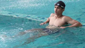 asiatisk män praktiserande simning och framställning till spela vatten polo och stretching och vilar för vatten sporter. video