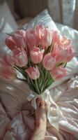 Pink Tulip Bouquet on White Bed Sheets in a Bedroom photo