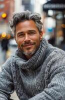 Portrait of a Smiling Man With Gray Hair and a Gray Knit Sweater in a City Setting photo