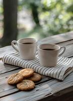 Two Cups of Coffee and Cookies on a Striped Napkin on a Wooden Table photo