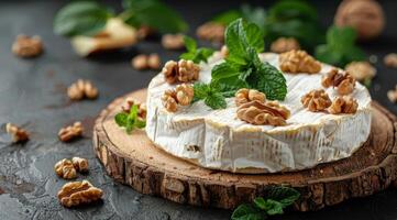 A Creamy Brie Wheel With Walnuts and Mint on a Wooden Board photo