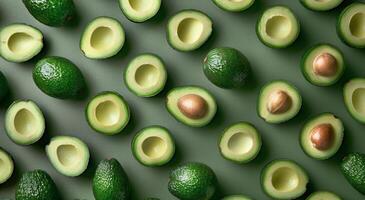 Whole and Halved Avocados Arranged on a Green Surface photo