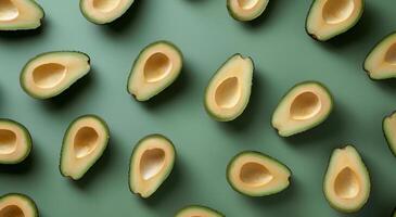 Whole and Halved Avocados Arranged on a Green Surface photo