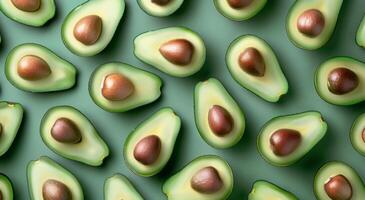 Whole and Halved Avocados Arranged on a Green Surface photo