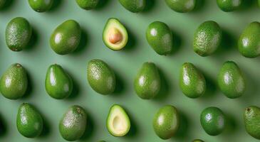 Whole and Halved Avocados Arranged on a Green Surface photo
