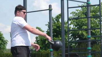 Esportes e lazer. Forte caucasiano homem trabalhando Fora usando kettlebell dentro a parque video