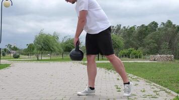 Deportes y ocio. fuerte caucásico hombre trabajando fuera utilizando pesas rusas en el parque video