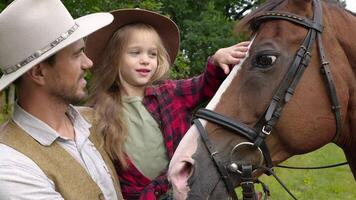 vaqueiro e dele filha acariciando uma cavalo. feliz vaqueiro família. fechar-se, lento movimento. video