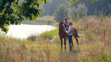 Cowboy and his daughter on horseback on the river bank. Happy cowboy family. Slow motion. video