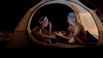 zoon en vader in een tent Bij nacht. vrijheid en reizen concept. 4k video