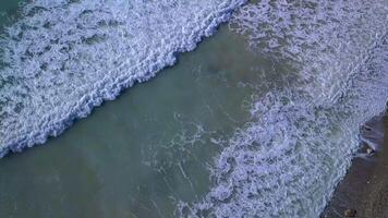 Aerial top view waves break on beach. Sea waves on the beautiful beach aerial view drone. 4k video