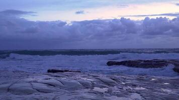 storm vågor kraschar stenar kust. dramatisk himmel i de kväll. 4k video