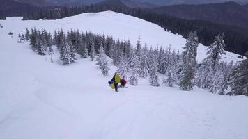 Flying over a group of tourists with backpacks in the winter mountains. Winter climbing in the Carpathian Mountains. Snowy tree branch in a view of the winter forest. Aerial footage, 4K video