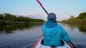 une femme est kayak sur une calme rivière. elle est aviron avec avirons. 4k video
