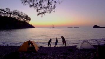 padre e bambini fare fitness nel il mattina. gli sport famiglia su il spiaggia. 4k video