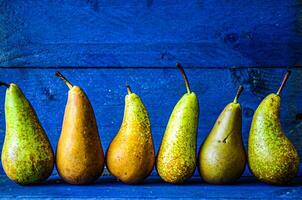 Original natural pears stand in a row on a blue background. photo