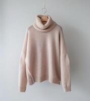 A Pink Sweater Hanging on a White Wall photo