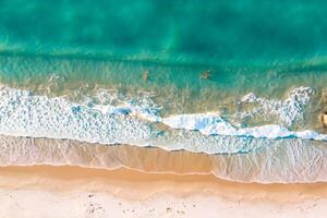 hermosa playa ver desde encima blanco playa y azul olas crear un asombroso costero escena, ofrecimiento serenidad y tranquilidad en de la naturaleza espléndido lona foto