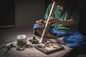 A man prepares marijuana on a cutting board to smoke, person who smokes drugs, drug addict, Drugs addiction and withdrawal symptoms concept. drugsInternational Day against Drug Abuse. photo