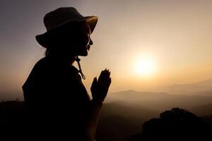 silueta de persona mujer demostrando su religioso fe. mujer mano en oración, expresando su religioso fe en Dios mediante Adoración de Jesús cristo.convertido a Dios en oración. foto