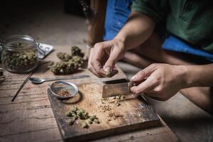 A man prepares marijuana on a cutting board to smoke, person who smokes drugs, drug addict, Drugs addiction and withdrawal symptoms concept. drugsInternational Day against Drug Abuse. photo