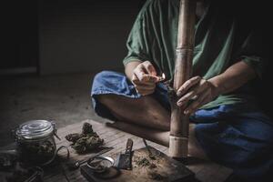 un hombre prepara marijuana en un corte tablero a fumar, persona quien fuma drogas, fármaco adicto, drogas adiccion y retirada síntomas concepto. drogasinternacional día en contra fármaco abuso. foto