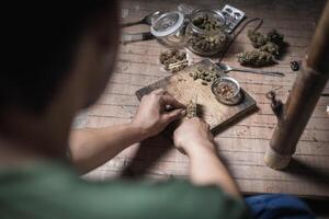 A man prepares marijuana on a cutting board to smoke, person who smokes drugs, drug addict, Drugs addiction and withdrawal symptoms concept. drugsInternational Day against Drug Abuse. photo