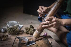 A man prepares marijuana on a cutting board to smoke, person who smokes drugs, drug addict, Drugs addiction and withdrawal symptoms concept. drugsInternational Day against Drug Abuse. photo