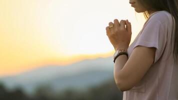 young woman clasped her hands together in prayer asking for forgiveness from God based on her Christian beliefs and faith in God teachings. concept prayer and intercession according beliefs about God photo