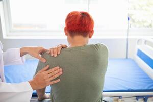 man was admitted for treatment of muscle pain in back of his shoulder due to working hard and causing muscle inflammation. doctor is treating man muscle pain in his back and shoulders due to overwork. photo