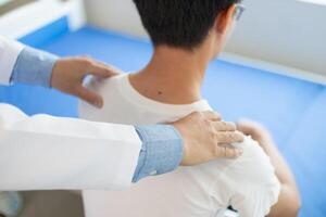 man was admitted for treatment of muscle pain in back of his shoulder due to working hard and causing muscle inflammation. doctor is treating man muscle pain in his back and shoulders due to overwork. photo