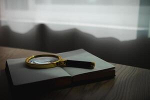 A Bible and a magnifying glass are placed on a wooden table after praying to God Christian religious ritual and belief in the teachings of God. Ideas for praying to God with teachings from the Bible photo