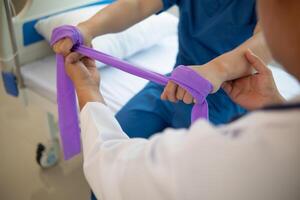 doctor is examining muscle injury and using elastic bands test injury and also help with physical therapy strengthen muscles because physical therapy will help strengthen muscles and help blood flow. photo