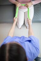 female doctor using elastic bands help patient regain muscle movement after recuperating from muscle injury and wants rehabilitate her be able use her normal daily life by practicing physical therapy photo