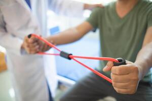 female doctor using elastic bands help patient regain muscle movement after recuperating from muscle injury and wants rehabilitate her be able use her normal daily life by practicing physical therapy photo