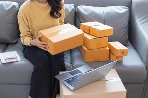 businesswoman decides invest in small SME business at home by using laptop and smartphone do online marketing and sell things online through an application before packing products according to orders. photo