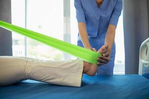 female doctor using elastic bands help patient regain muscle movement after recuperating from muscle injury and wants rehabilitate her be able use her normal daily life by practicing physical therapy photo