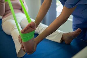 female doctor using elastic bands help patient regain muscle movement after recuperating from muscle injury and wants rehabilitate her be able use her normal daily life by practicing physical therapy photo