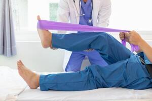 female doctor using elastic bands help patient regain muscle movement after recuperating from muscle injury and wants rehabilitate her be able use her normal daily life by practicing physical therapy photo