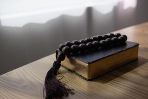 Bible and rosary placed on a wooden table after praying to God which is a Christian religious ritual and belief in the teachings of God. Ideas for praying to God with teachings from the Bible photo