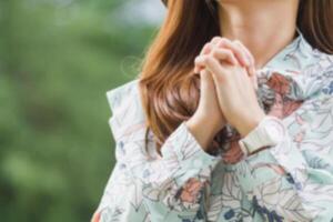 young woman clasped her hands together in prayer asking for forgiveness from God based on her Christian beliefs and faith in God teachings. concept prayer and intercession according beliefs about God photo