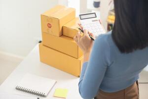 SME business operator is inspecting and packing products into parcel box for delivery company that will come pick up products after participating in online marketing with Application shopping online photo
