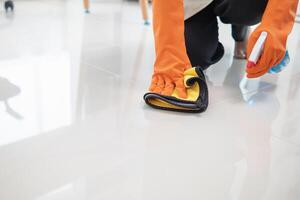 young woman puts on an apron and rubber gloves before holding spray bottle filled with cleaner and disinfectant to use to clean furniture surfaces clean and germ free. Concept of contract Hire cleaner photo