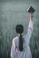 The young woman held a Bible in her hand and tried to learn and understand God teachings from the Bible she held. Concepts of belief and the power of faith in God and teachings from the Bible. photo