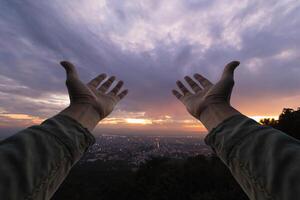 man raised her hands above her head to ask for mercy from God in accordance with her belief in God in Christianity. man raising both hands to ask for blessings from God according to beliefs photo