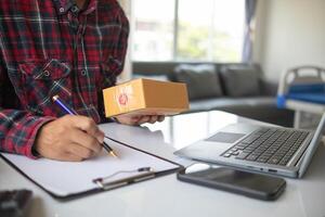businessman decides invest in small SME business at home by using laptop and smartphone do online marketing and sell things online through an application before packing products according to orders. photo