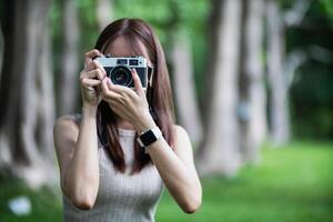 young photographer holds vintage style film camera in her hand and inspects film camera for use after film cameras have become popular with photographers today because of their unique image tones. photo