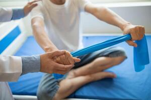 female doctor using elastic bands help patient regain muscle movement after recuperating from muscle injury and wants rehabilitate her be able use her normal daily life by practicing physical therapy photo